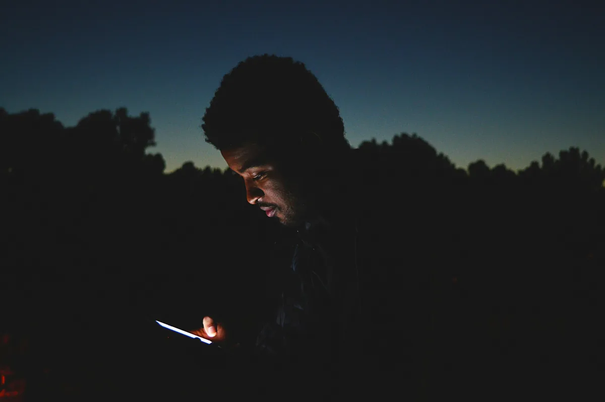 Akşam karanlığında telefonuna bakan bir kişi